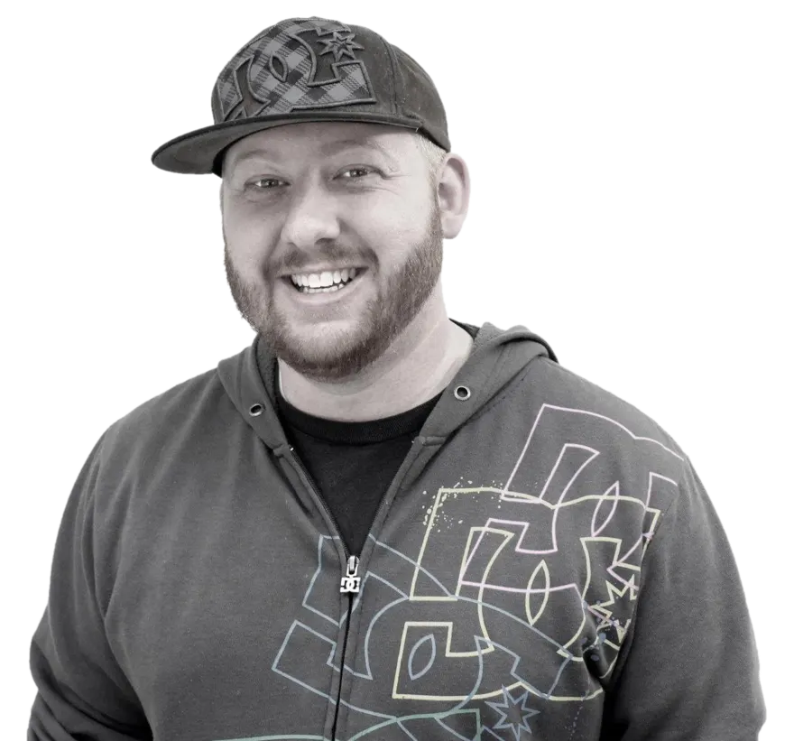 Eric Schmiedel smiling, wearing a flat-brim cap and a graphic hoodie